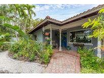 Charming home featuring lush landscaping, a brick walkway, and a welcoming covered front porch at 501 Sloop Ln, Longboat Key, FL 34228