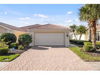 Charming home exterior featuring a brick driveway, two car garage, lush landscaping, and tile roof at 5509 Avellino Pl, Sarasota, FL 34238
