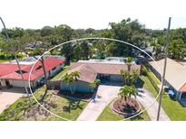 A charming single-Gathering home with a circular driveway is surrounded by lush landscaping and mature palm trees at 7019 10Th S St, St Petersburg, FL 33705