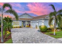 Beautiful single-story home featuring a paver driveway, lush landscaping, and a three-car garage at 8258 Grande Shores Dr, Sarasota, FL 34240