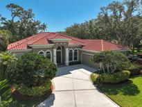 Stunning single story home featuring a red tile roof, neutral paint, manicured landscaping and a circular driveway at 901 Reflection Way, Osprey, FL 34229