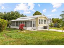 Charming yellow home with a screen porch, green lawn and colorful foliage in a sunny setting at 182 Crown Point Dr, Nokomis, FL 34275