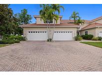 Spacious red brick driveway leading to a home with a two-car garage and lush landscaping at 197 Tropicana Dr # 1511, Punta Gorda, FL 33950