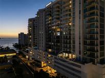 Exterior view of the high-rise building showing a private outdoor patio with furniture and the city in the background at 301 Quay Commons # 507, Sarasota, FL 34236