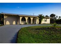 Charming home featuring a large, paved driveway and a well-manicured lawn at 389 Millport Nw St, Port Charlotte, FL 33948