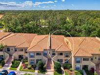 View of a two-story condo featuring a red tile roof, beige siding and manicured landscaping at 4489 Longmeadow # 74, Sarasota, FL 34235