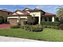 Charming home featuring lush landscaping, a tile roof, and a two-car garage at 4622 Grand Lakeside Dr, Palm Harbor, FL 34684