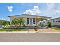 Charming single-story home featuring a covered carport, landscaped front yard, and inviting entryway with palm trees at 5619 Bayshore Rd # 211, Palmetto, FL 34221