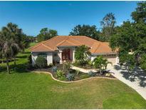 Charming single-story home with a tile roof, red double-door entry, and tropical landscaping at 2183 Muskogee Trl, Nokomis, FL 34275