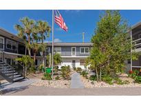 Inviting two-story condo with a landscaped courtyard, stairs to the left, and an American flag in the center at 236 Harbor S Dr # 205, Venice, FL 34285