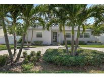 Charming home showcasing mature palm trees, a well-manicured lawn, and an inviting front facade at 322 35Th Ne Ave, St Petersburg, FL 33704