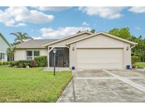 Charming single-story home featuring a two-car garage and a well-maintained front yard with lush landscaping at 338 Indian Key Way # 111, Englewood, FL 34223