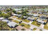 This aerial view shows a neighborhood with single-Gathering homes and a serene lake at 440 Redwood Rd, Venice, FL 34293