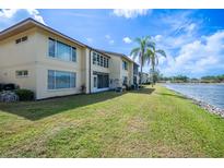 Exterior view of the condo with a lake and lush green lawn with palm trees in the background at 4454 Narraganset Trl # 94A, Sarasota, FL 34233