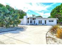 Striking single story home with a light gray exterior, chimney, and large driveway with decorative rocks at 6115 6Th Nw Ave, Bradenton, FL 34209