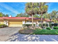 Inviting home featuring a red tile roof, two-car garage, and mature landscaping with palm trees at 6414 Sun Eagle Ln, Bradenton, FL 34210