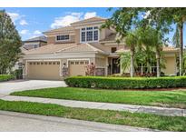 Stunning two-story home featuring a three-car garage, well-manicured lawn, and beautiful tropical landscaping at 6532 Coopers Hawk Ct, Lakewood Ranch, FL 34202