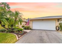 Charming home featuring lush landscaping, palm trees, and a welcoming two-car garage at 6940 W Country Club N Dr # V-77, Sarasota, FL 34243