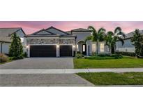 Beautiful single-Gathering home featuring a manicured lawn, stone accents, and a two-car garage with a paved driveway at 8033 Grande Shores Dr, Sarasota, FL 34240