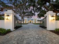 Elegant home with a long driveway and beautiful landscaping, featuring a gated entrance and lush greenery at 8155 Midnight Pass Rd, Sarasota, FL 34242