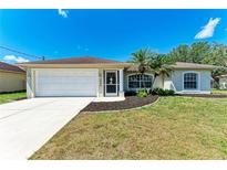 Charming single-story home featuring a well-maintained lawn and beautiful landscaping with young palm trees at 1323 Arredondo St, North Port, FL 34286