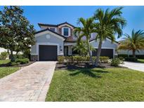 Beautiful two-story home boasts a well-manicured lawn, paver driveway, a two-car garage and lush tropical landscaping at 13409 Ramblewood Trl, Bradenton, FL 34211