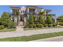 Elegant multi-story home with manicured landscaping, iron gate, and private balconies on a sunny day at 212 Milan W Ave # 1, Venice, FL 34285