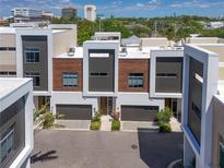 Modern townhomes featuring a combination of neutral tones, woodgrain accents, and private garage entries at 221 Cosmopolitan Ct, Sarasota, FL 34236