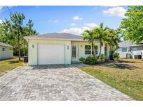 Charming single-story home featuring a well-maintained lawn, palm trees, and a brick driveway leading to an attached garage at 2840 S Shade Ave, Sarasota, FL 34239
