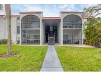 Condo building with stucco exterior, red tile roof, and open balconies overlooking a green lawn at 3251 Beneva Rd # 104, Sarasota, FL 34232