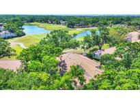 An aerial view of the roof and surrounding landscape including a lake, a golf course, and plenty of mature trees at 3916 Chatsworth Greene # 3, Sarasota, FL 34235