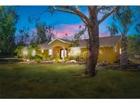 Charming yellow single-story home with manicured lawn, lush landscaping, and inviting double-door entrance at 6217 Goldfinch St, Sarasota, FL 34241
