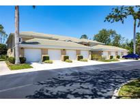Beige condo building with a row of garages, manicured landscaping, and a glimpse of a blue car at 6334 Grand Oak Cir # 202, Bradenton, FL 34203