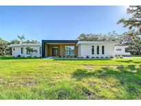 Modern home featuring a sleek, minimalist design with lush green lawn and manicured landscaping at 7200 Chameleon Way, Sarasota, FL 34241