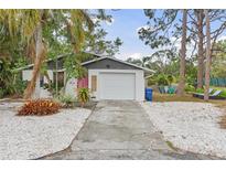 Charming home showcasing a cute pink door, a white garage, and a well-maintained landscaped yard at 7795 Wright Ave, Sarasota, FL 34231