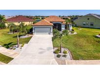 Charming single-story home with a well-manicured lawn, palm trees, and a two-car garage at 12830 24Th Street E Cir, Parrish, FL 34219