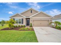 Charming home featuring a manicured lawn, a two-car garage, and tasteful landscaping for curb appeal at 16341 Little Garden Dr, Wimauma, FL 33598