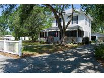 Charming two-story home with a white picket fence, mature trees, and a welcoming front porch at 1704 4Th W St, Palmetto, FL 34221