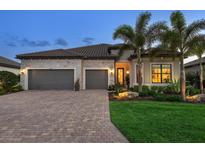 Beautiful exterior featuring a brick driveway, a two-car garage, stone accents and professionally landscaped yard at 17820 Waterville Pl, Lakewood Ranch, FL 34202