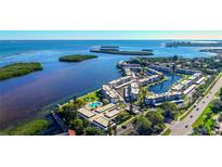 Stunning aerial view of waterfront condos with pool, boat docks, and lush landscaping, offering serene coastal living at 4350 Chatham Dr # E-105, Longboat Key, FL 34228