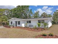 Charming single-story white home featuring a well-maintained lawn with mulch and updated landscaping at 4823 Linwood St, Sarasota, FL 34232