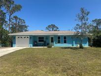 Charming blue single-story home featuring a well-maintained lawn, inviting facade, and pristine white trim at 534 Lewis St, Englewood, FL 34223
