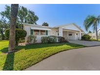 Charming single-story home featuring a well-manicured lawn, carport, and a beautifully maintained front yard with mature landscaping at 6087 Coral Way, Bradenton, FL 34207