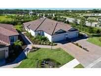Stunning aerial view of a single-story home featuring a tile roof, three-car garage, and beautiful landscaping at 6308 Plateau Ct, Bradenton, FL 34203