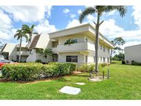 Well-maintained condo building with lush landscaping, mature palms, and bright sunny skies at 7173 W Country Club N Dr # 141, Sarasota, FL 34243