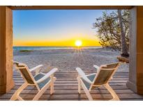 Stunning sunset view from beachside home with two chairs on the porch overlooking the ocean at 8592 Hidden Lagoon Rd, Sarasota, FL 34242