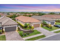 Beautiful single-story home with a terracotta-colored tile roof, lush landscaping, and a two-car garage at 8721 Trattoria Ter, Sarasota, FL 34238
