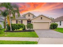 Charming single-Gathering home featuring a well-manicured lawn, lush landscaping, and a brick-paved driveway at 12592 Ryegrass Loop, Parrish, FL 34219
