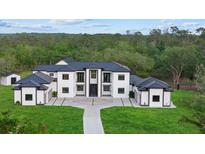 Stunning modern home with a black metal roof, white exterior, and lush green lawn at 20307 74Th E Ave, Bradenton, FL 34202