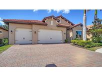 Stunning home with a red tile roof and a brick driveway leading to a two-car garage at 227 Maraviya Blvd, Nokomis, FL 34275